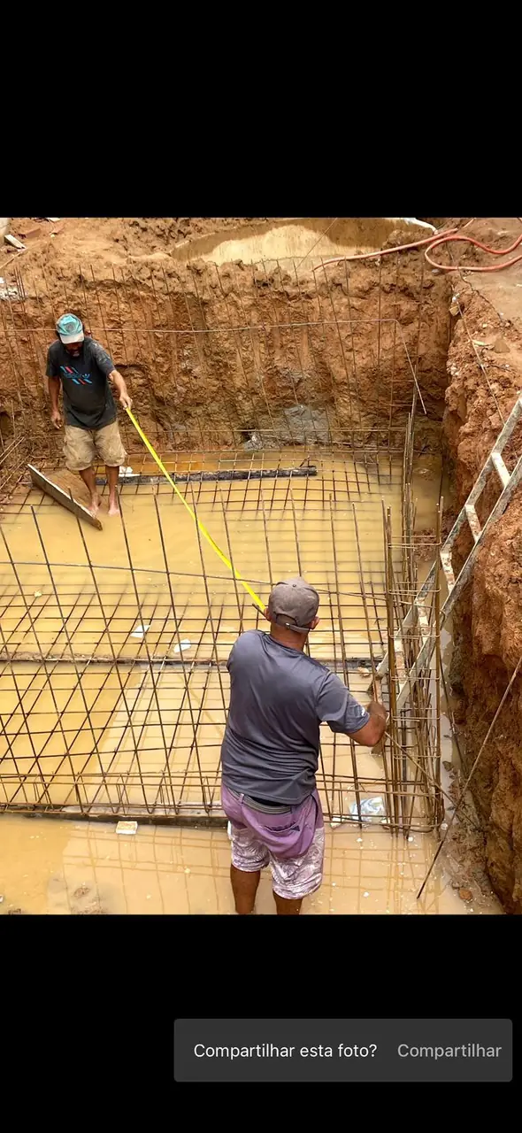 Trabalhadores preparando a estrutura da piscina no terreno escavado