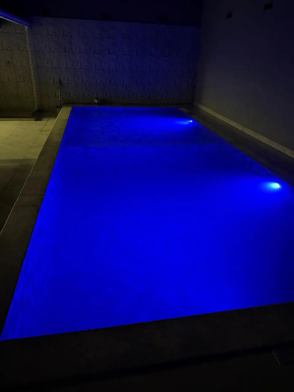 Piscina com iluminação azul em etapa de acabamento