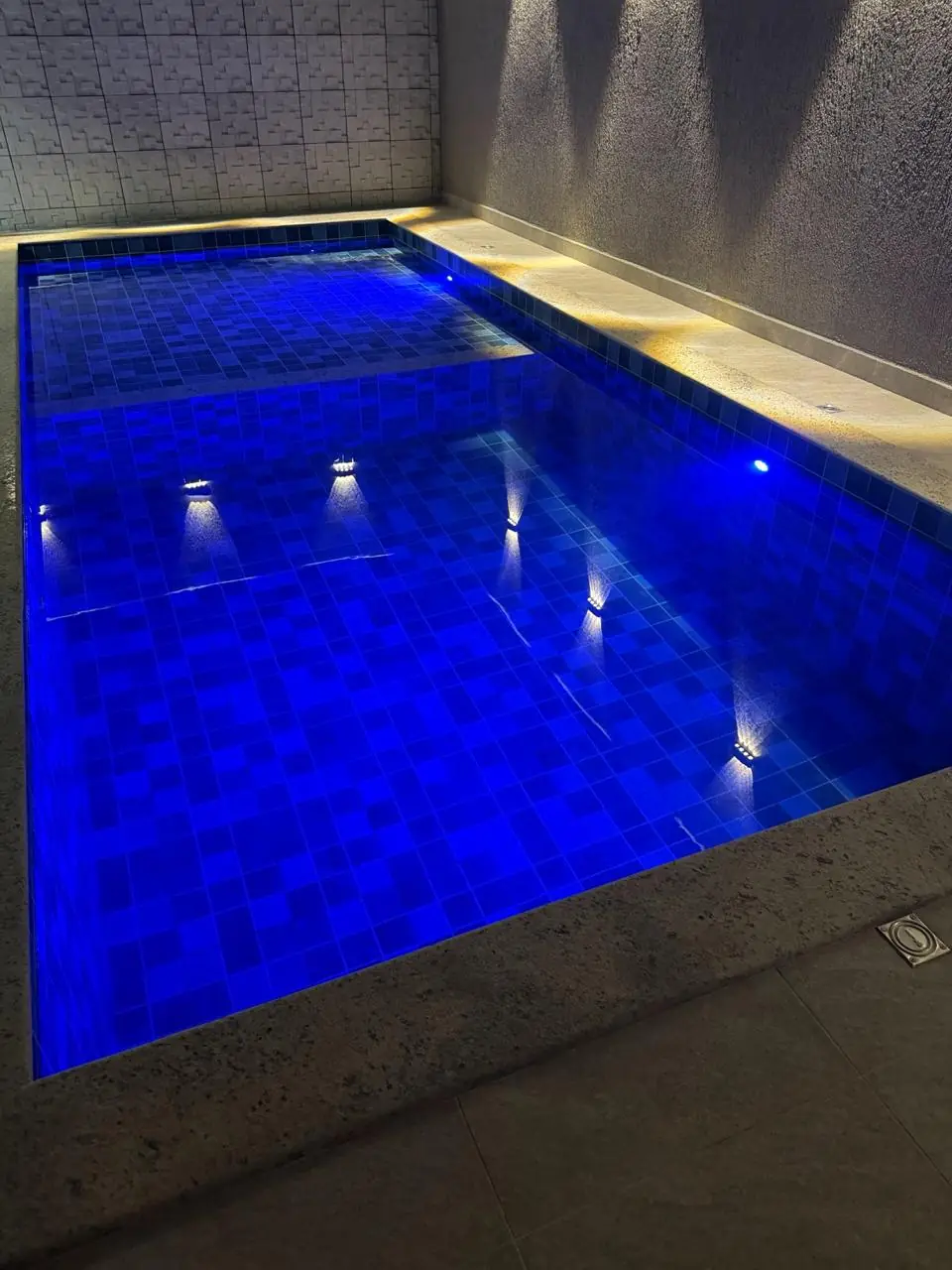 Piscina revestida com pastilhas azuis e acabamento instalado