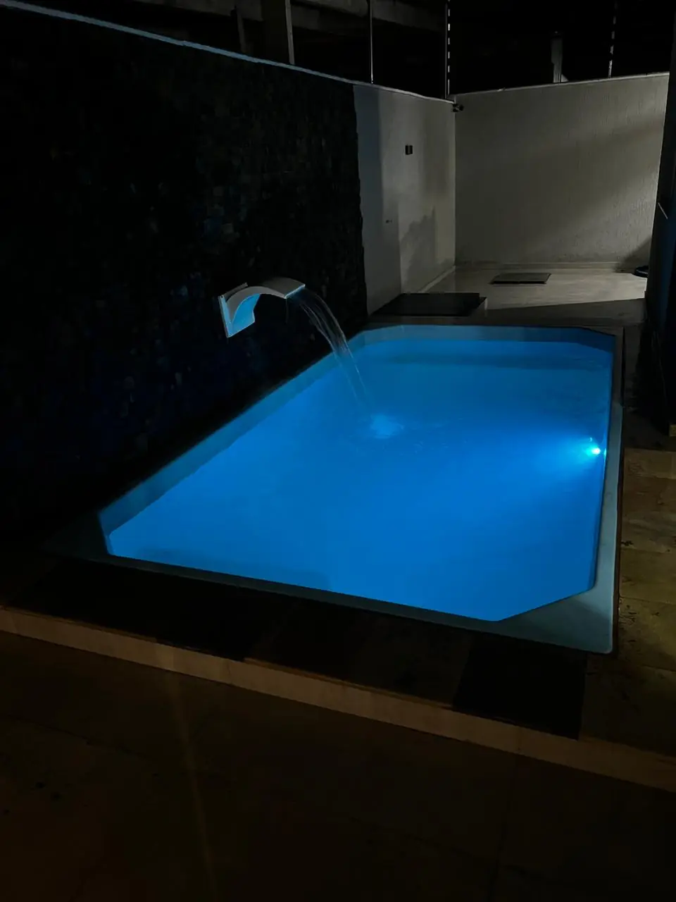 Piscina pronta com iluminação azul em ambiente noturno